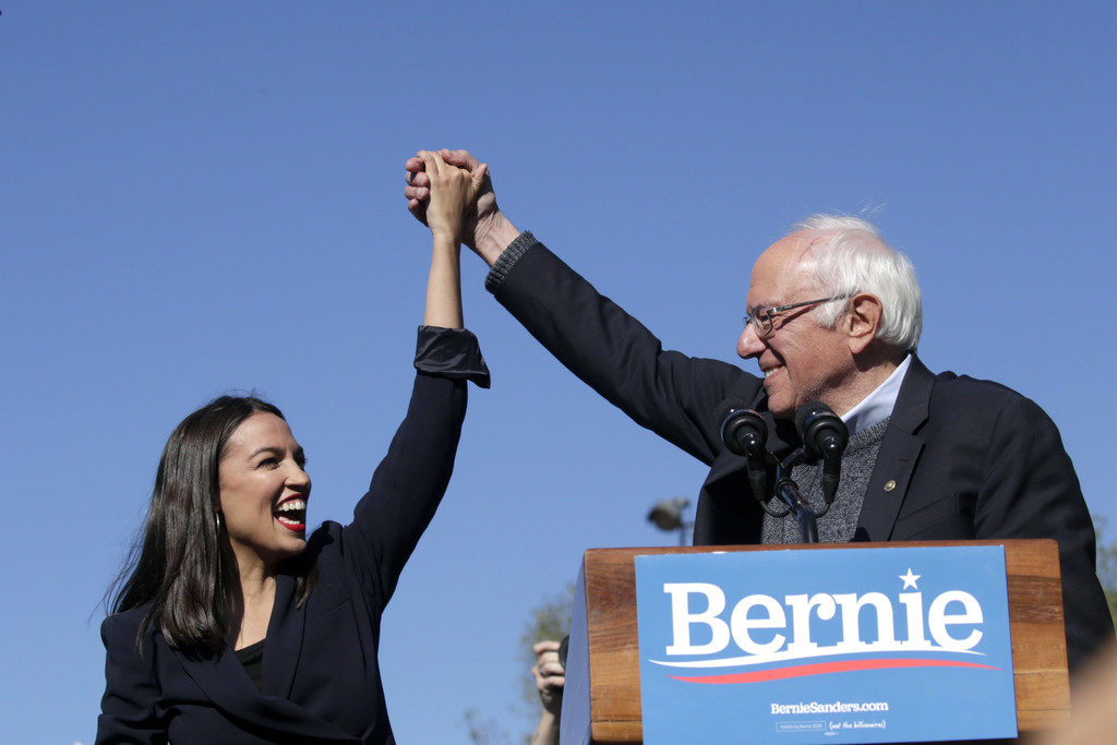 Democratic presidential candidate, Sen. Bernie Sanders (I-VT) holds hands with Rep. Alexandria Ocasio-Cortez